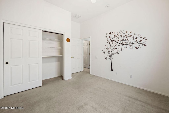 unfurnished bedroom with light colored carpet and a closet