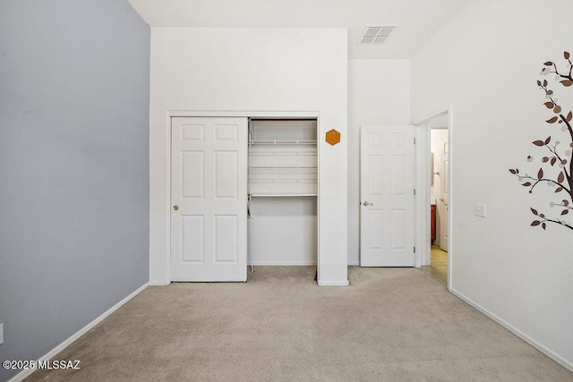 unfurnished bedroom with light carpet and a closet