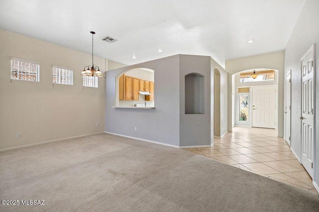 carpeted entrance foyer featuring a notable chandelier