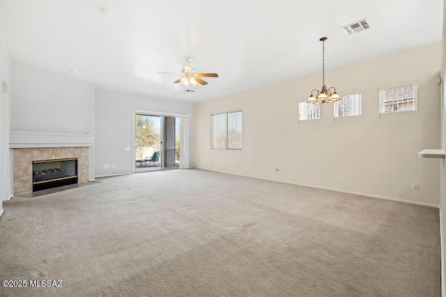 unfurnished living room with a tile fireplace, ceiling fan with notable chandelier, and light carpet