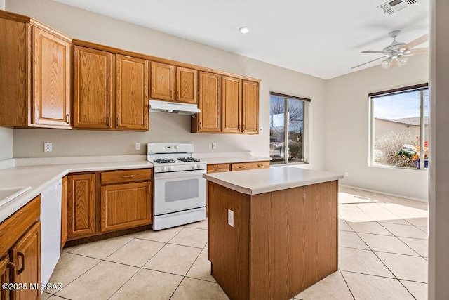 kitchen with light tile patterned flooring, white appliances, a center island, and ceiling fan