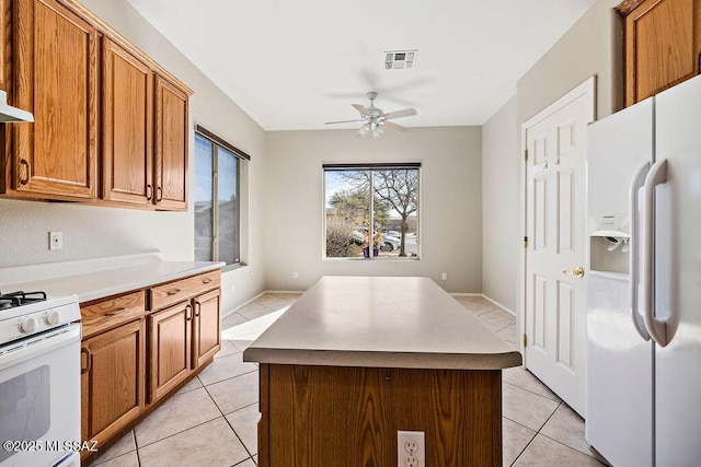 kitchen with light tile patterned flooring, white appliances, ceiling fan, and a kitchen island