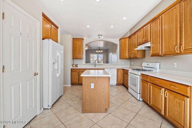 kitchen with sink, white appliances, light tile patterned flooring, and a kitchen island