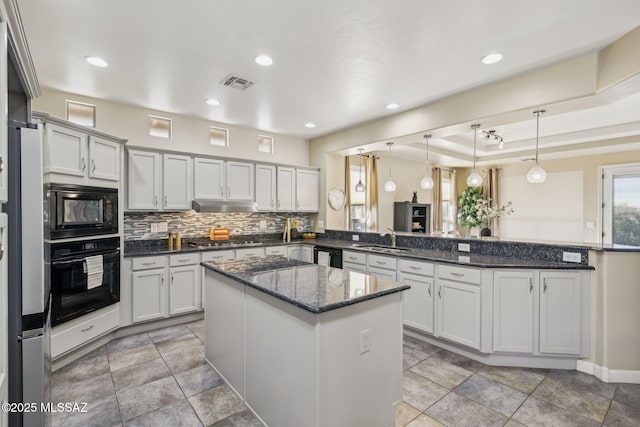 kitchen with sink, black appliances, decorative light fixtures, kitchen peninsula, and dark stone counters