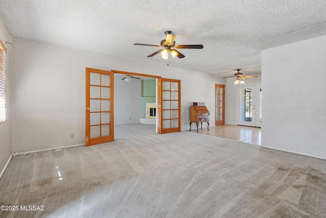 unfurnished room with ceiling fan, a textured ceiling, carpet flooring, and french doors