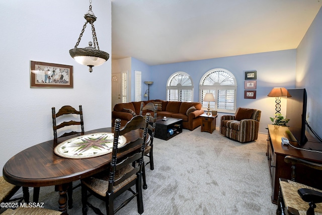 carpeted dining space with lofted ceiling