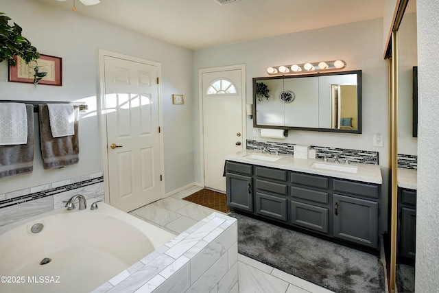 bathroom with vanity, backsplash, and tiled bath