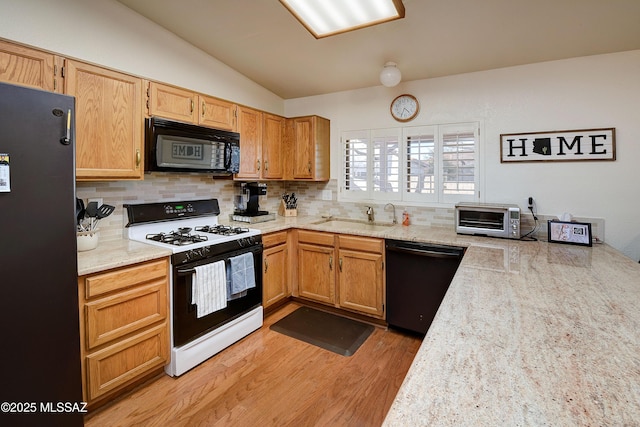 kitchen featuring sink, backsplash, black appliances, vaulted ceiling, and light wood-type flooring