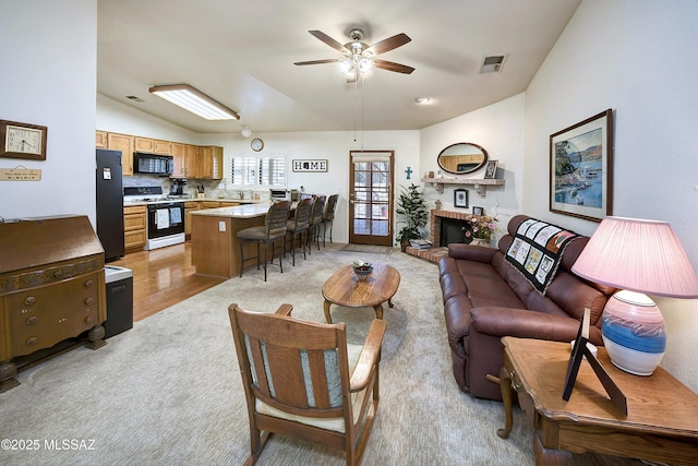 living room featuring ceiling fan, lofted ceiling, and a brick fireplace