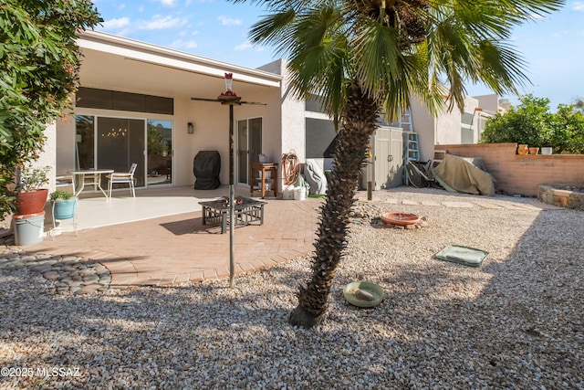 back of house with ceiling fan, an outdoor fire pit, and a patio