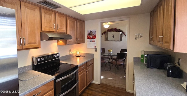 kitchen featuring under cabinet range hood, dark wood-type flooring, visible vents, appliances with stainless steel finishes, and brown cabinetry