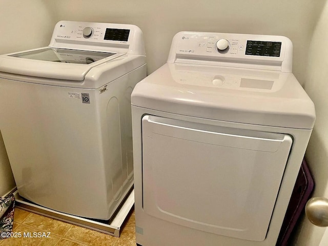 laundry area with washer and clothes dryer and light tile patterned floors