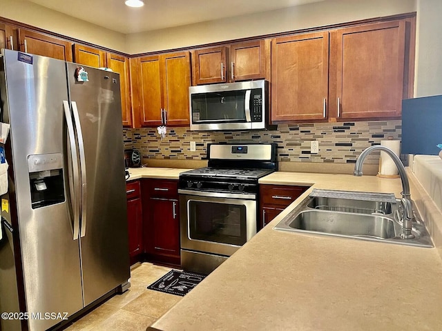 kitchen with tasteful backsplash, appliances with stainless steel finishes, sink, and light tile patterned floors