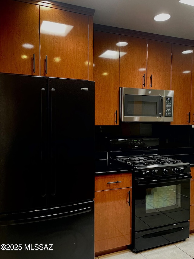 kitchen featuring backsplash, light tile patterned flooring, and black appliances