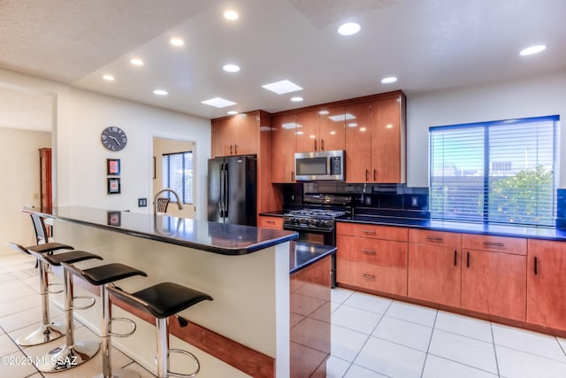 kitchen featuring a kitchen island, a kitchen breakfast bar, decorative backsplash, light tile patterned floors, and black appliances