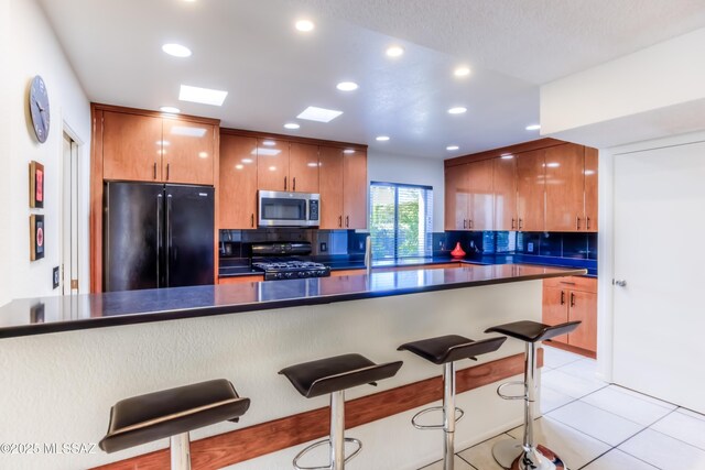 kitchen featuring sink, light tile patterned floors, a textured ceiling, and black appliances