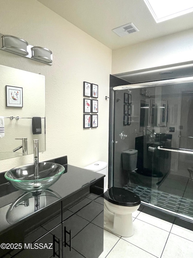 bathroom featuring tile patterned floors, toilet, an enclosed shower, and sink