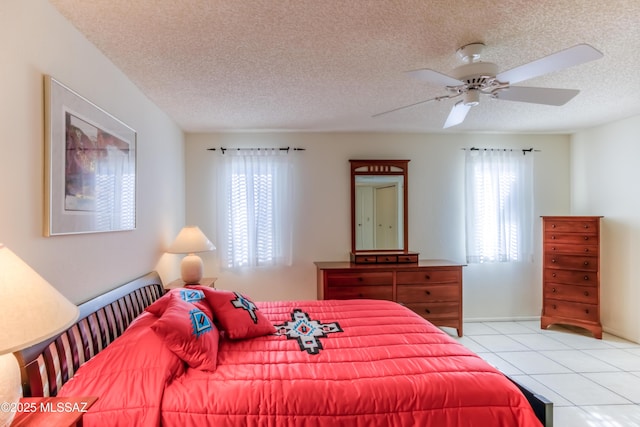 bedroom featuring ceiling fan, light tile patterned floors, and a textured ceiling