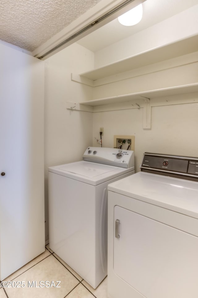 laundry room with light tile patterned floors, a textured ceiling, and washing machine and clothes dryer