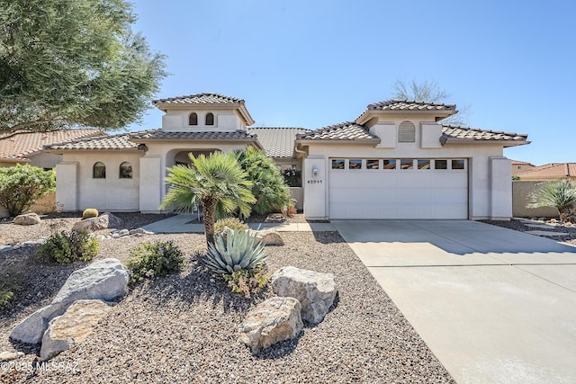 mediterranean / spanish home featuring a tiled roof, a garage, driveway, and stucco siding