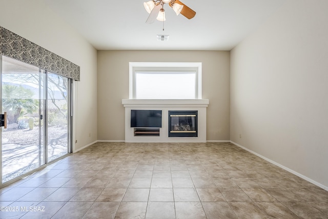 unfurnished living room with light tile patterned floors, visible vents, baseboards, and a glass covered fireplace