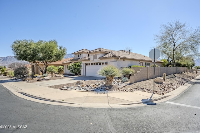 mediterranean / spanish-style home featuring fence, a tiled roof, concrete driveway, stucco siding, and a garage