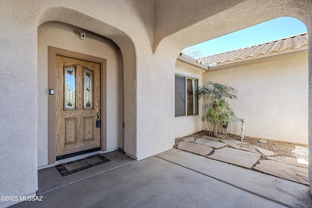 doorway to property featuring a patio area, stucco siding, and a tile roof