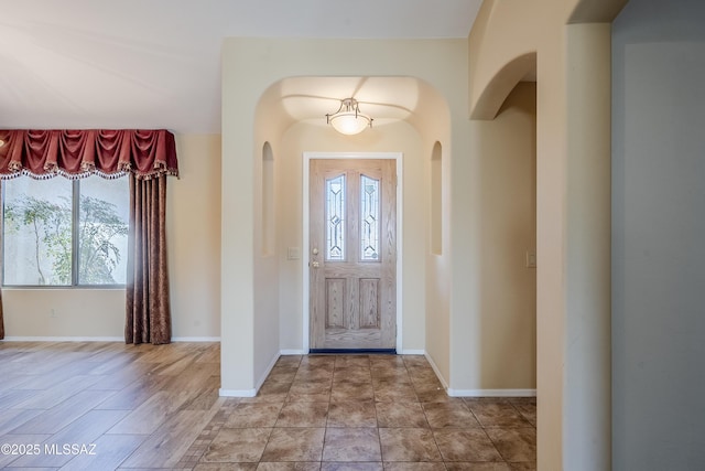 foyer entrance with baseboards and arched walkways