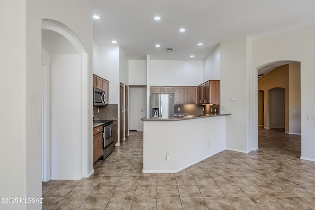 kitchen featuring tasteful backsplash, visible vents, appliances with stainless steel finishes, a peninsula, and arched walkways