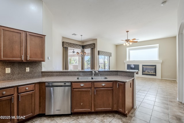 kitchen with visible vents, ceiling fan, a peninsula, a glass covered fireplace, and a sink