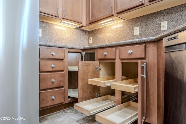 interior details with tasteful backsplash, brown cabinets, and freestanding refrigerator