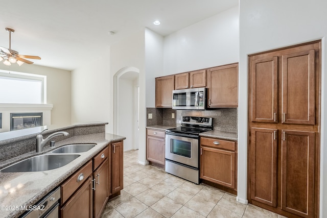 kitchen with a sink, decorative backsplash, appliances with stainless steel finishes, and brown cabinetry