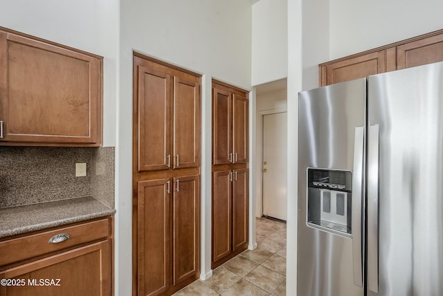 kitchen with backsplash, stainless steel fridge, and brown cabinets