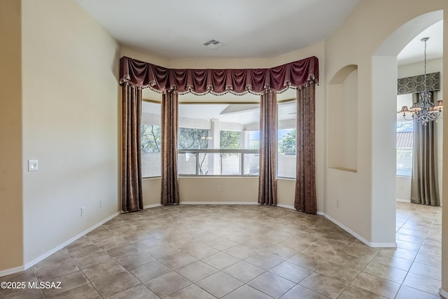 tiled spare room with visible vents, baseboards, a notable chandelier, and a healthy amount of sunlight