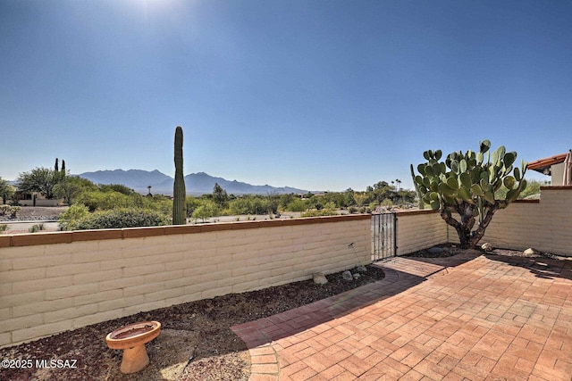 view of patio / terrace with a fenced backyard, a gate, and a mountain view