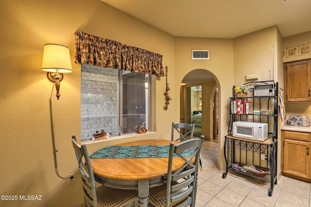 dining room featuring arched walkways, visible vents, and light tile patterned floors