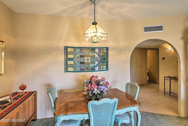 dining space featuring arched walkways, visible vents, an inviting chandelier, a textured ceiling, and tile patterned flooring