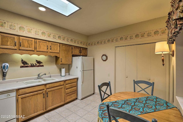 kitchen featuring light tile patterned floors, white appliances, a sink, light countertops, and brown cabinetry