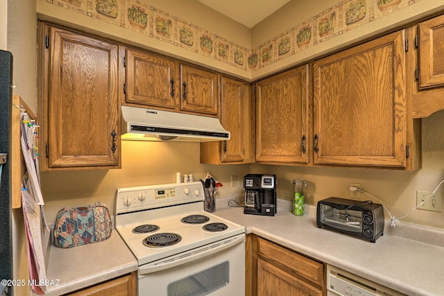 kitchen with brown cabinetry, range hood, white appliances, and light countertops