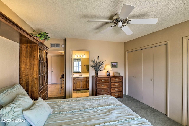 bedroom with visible vents, a ceiling fan, carpet flooring, connected bathroom, and a textured ceiling