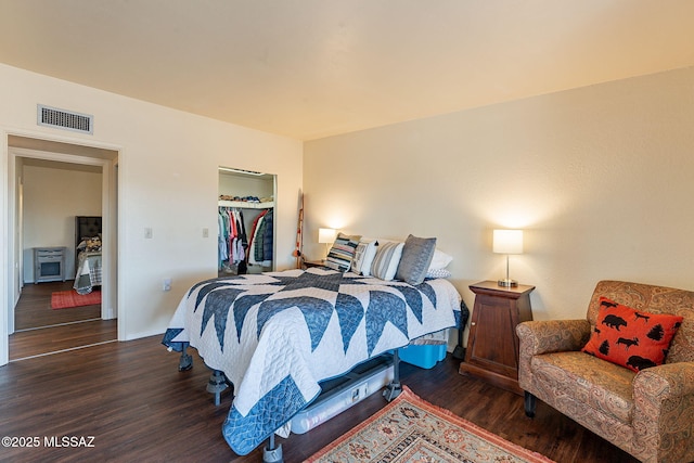 bedroom featuring a walk in closet, dark hardwood / wood-style flooring, and a closet