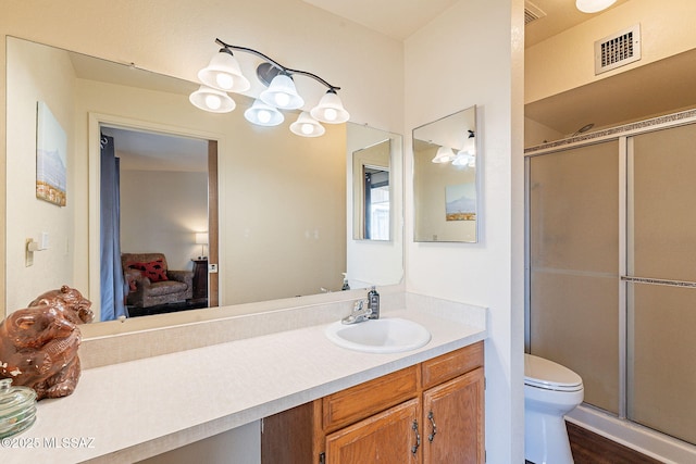 bathroom featuring vanity, toilet, and a shower with door