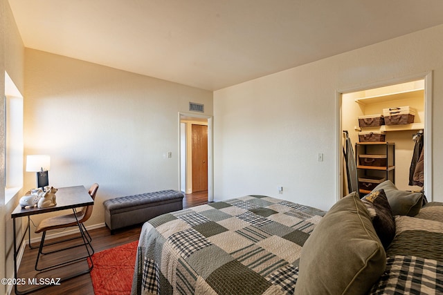 bedroom with a walk in closet and dark hardwood / wood-style floors