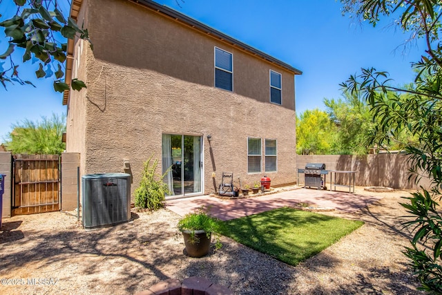 back of property with central AC and a patio