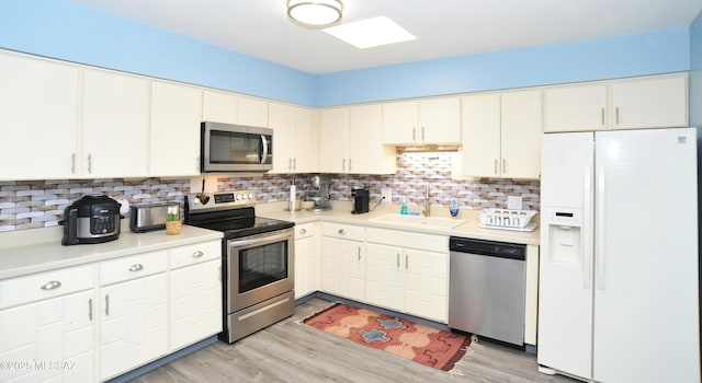 kitchen with sink, white cabinets, backsplash, light hardwood / wood-style floors, and stainless steel appliances