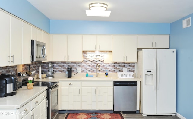 kitchen featuring tasteful backsplash, sink, stainless steel appliances, and white cabinets