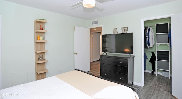 bedroom with dark hardwood / wood-style flooring, a walk in closet, a closet, and ceiling fan