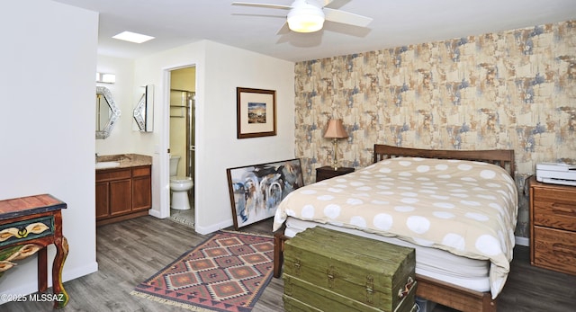 bedroom with ensuite bathroom, dark hardwood / wood-style floors, and ceiling fan