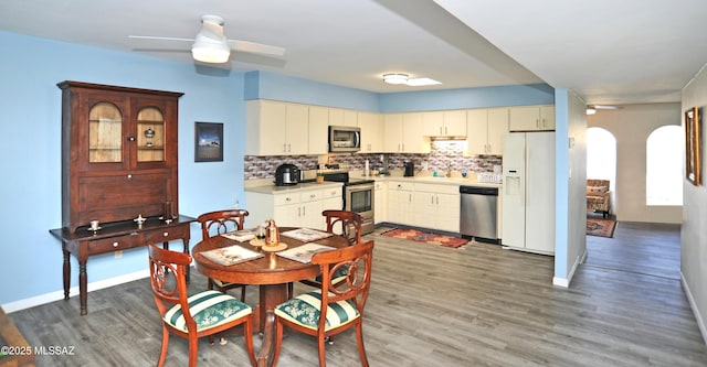 kitchen featuring decorative backsplash, dark wood-type flooring, ceiling fan, and appliances with stainless steel finishes