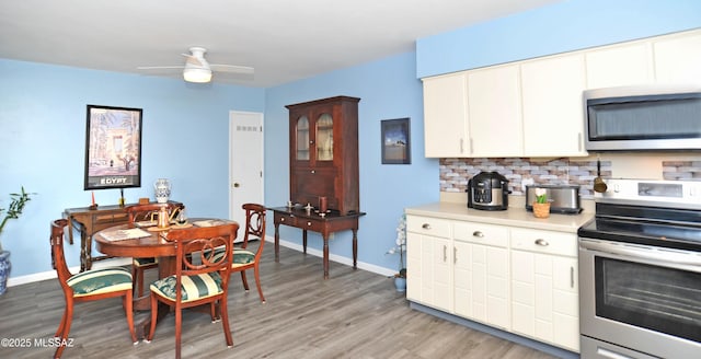 kitchen featuring appliances with stainless steel finishes, white cabinetry, decorative backsplash, ceiling fan, and light wood-type flooring